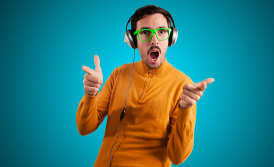 Education and modern technologies. The concept of audio books. A bald man in glasses with closed eyes and a smile, listening to the reading of a book through headphones. Yellow background. Close up.